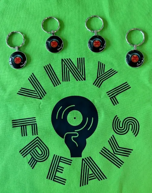 Bright green bag with a vinyl record logo held by a fist and the words VINYL FREAKS in a circular pattern; four keychain records above.